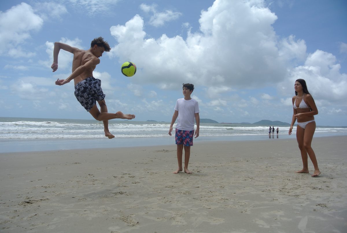 Mid-air bicycle kick with a soccer ball on a Brazilian beach.