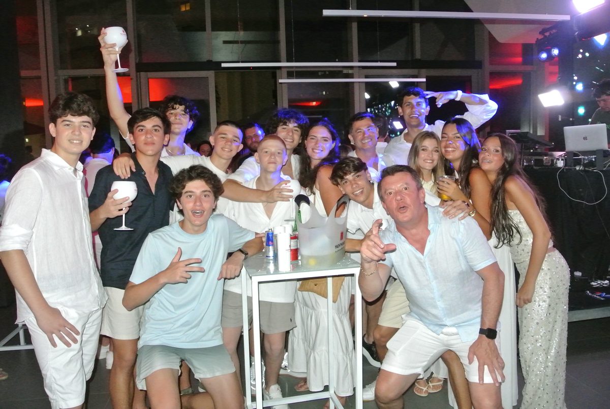 A big group celebrating together at a party, everyone in white.