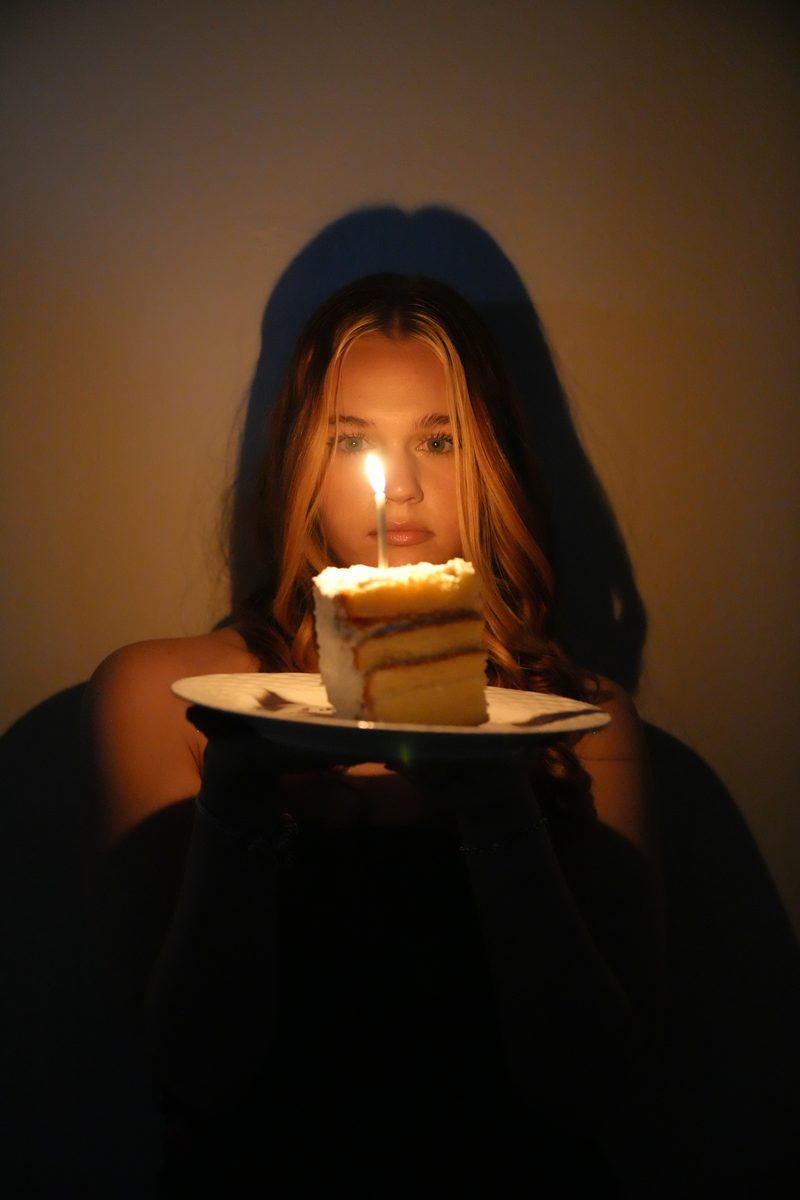 Birthday portrait lit only by a candle on a slice of cake.