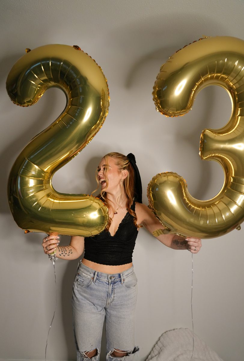 Candid laugh between gold 23 balloons.