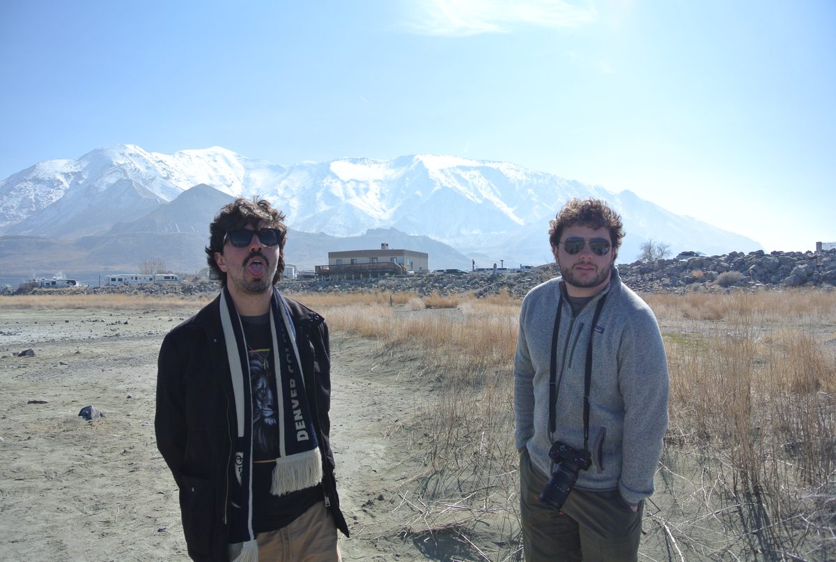 Two friends posing in front of snow-capped mountains in Utah.