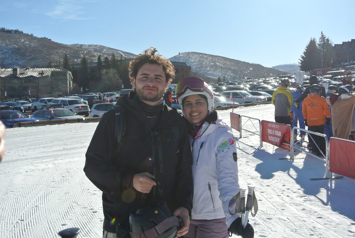 Two friends smiling at the base of a Utah ski resort.